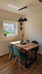 a dining room table with green chairs and a window at Apartmánový domček in Veľká Lomnica +21 photos