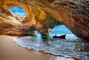 a boat in the water under a cave on the beach at T1 na 1 linha da Praia da Rocha in Portimão