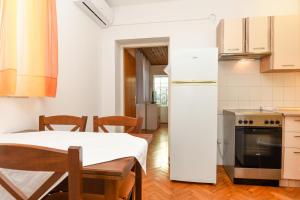 a kitchen with a table and chairs and a refrigerator at App Jadranka Matak in Rabac