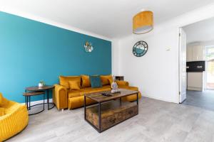 a living room with a yellow couch and a blue wall at Entire House - Contractor's, Families & More in Little Wymondley