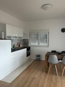 a kitchen with white cabinets and a wooden table at Galešnjak in Sveti Petar