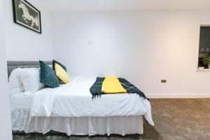 a white bed with pillows and a yellow blanket on it at Purley 2 Bed Flat in Purley