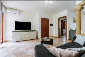 a living room with a couch and a tv at Villetta Gio in Olìa Speciosa