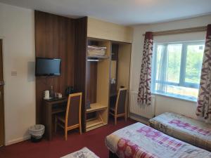 a hotel room with a bed and a desk and a window at The Gatwick White House Hotel in Horley