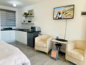 a room with a bed and two chairs and a kitchen at Mo Ville Guest House in Maseru