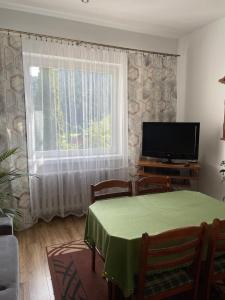 什恰夫尼察Szczawnica - Pokoje z widokiem na góry的客厅配有桌子、电视和窗户。