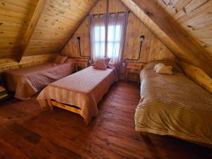 une chambre mansardée avec deux lits et une fenêtre dans l'établissement Cabañas en Los Reartes Córdoba, à Villa General Belgrano
