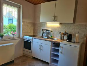 a kitchen with white cabinets and a sink and a window at Ferienhaus Am Becherberg in Schwarzenberg