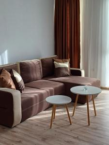 a living room with a brown couch and two tables at Апартамент Престиж 1 in Hisarya