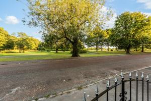 a road in a park with a fence and trees at Grand Victorian Villa 6 - En-Suites, Hot Tub, Cinema Room, Private Parking & Park View in Liverpool
