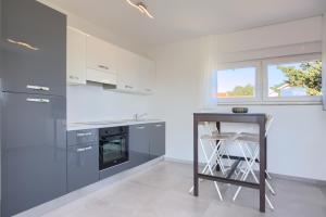 a kitchen with white cabinets and a table with a stool at Villa Harmony - Apartments in Banjole