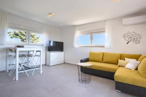 a living room with a yellow couch and a kitchen at Villa Harmony - Apartments in Banjole
