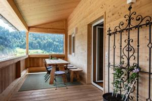 a wooden porch with a table and chairs on a deck at Ferienwohnungen am Dorfbach in Bezau