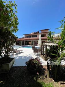 a pool with chairs and a umbrella and a building at Casa Praia Guaratuba - Bertioga in Bertioga