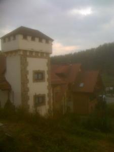 a building with a tower in front of a group of houses at Gosciniec Wenecja in Wisła