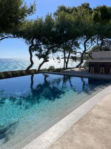 a swimming pool with trees and the ocean in the background at Bozonos Villa - Beachfront Simplicity with Heated Pool in Amoudi