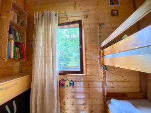 een kleine slaapkamer met een raam in een blokhut bij Leśny Domek in Kopalino