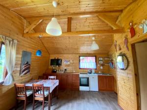 een keuken met een tafel en stoelen in een hut bij Leśny Domek in Kopalino +9 foto's