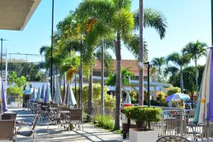 a patio with chairs and umbrellas and palm trees at OFERTA - Fiori DiRoma Caldas Novas - Térreo - Parque Aquático 24h in Caldas Novas