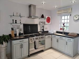 a kitchen with white cabinets and a stove top oven at Beautiful villa less than 5 minutes from the beach in Jolly Harbour +5 photos