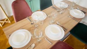 een houten tafel met witte borden en wijnglazen bij Le Jardin Suspendu, Steps to Lake & Station in Bussy-Saint-Georges