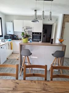 a kitchen with white cabinets and two stools at Foyer pagrita in Bretteville-sur-Odon