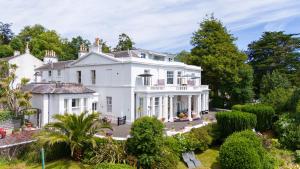 an exterior view of a white house with trees at Vomero Holiday Apartments in Torquay
