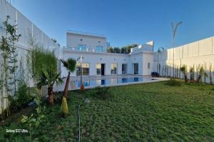 a large white building with a swimming pool next to a yard at Villa Fares Assilah 2 in Asilah