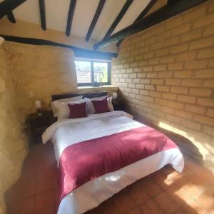 a bedroom with a large bed in a brick wall at Villa campestre San Vicente, Combita Boyacá in Cómbita