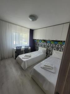 Una habitación de hotel con dos camas y un escritorio. en Al Mare Apartments - 39, en Constanţa