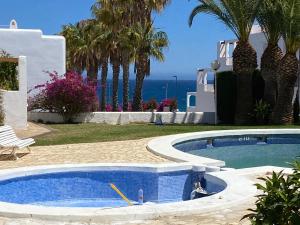 a swimming pool in front of a house with the ocean at Casa Los Remos in La Marina de la Torre