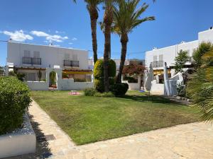 a yard with palm trees in front of a building at Casa Los Remos in La Marina de la Torre