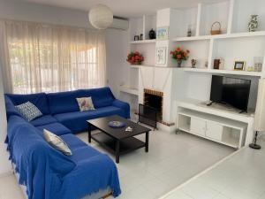 a living room with a blue couch and a tv at Casa Los Remos in La Marina de la Torre