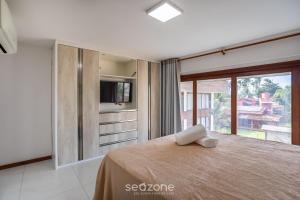 a bedroom with a bed with a television and a window at CPR - Apartamentos a 200m da praia com Piscina in Marau