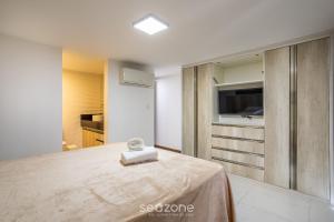 a room with a bed and a television in it at CPR - Apartamentos a 200m da praia com Piscina in Marau