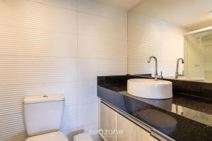 a bathroom with a white toilet and a sink at CPR - Apartamentos a 200m da praia com Piscina in Marau