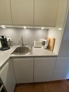 a kitchen with white cabinets and a sink and a counter at Sandbank in Langeoog