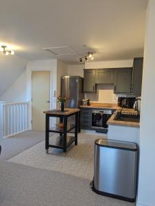 a kitchen with stainless steel appliances and a table at Two Bedroom Duplex Apartment in Swansea