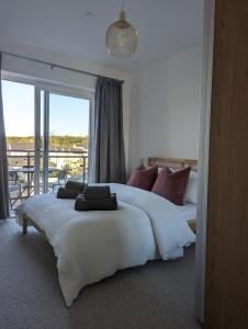 a bedroom with a large white bed with a balcony at Two Bedroom Duplex Apartment in Swansea