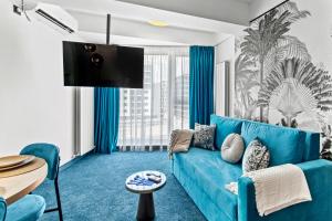 a living room with a blue couch and a tv at 5 Senses by Jorge in Infinity Pool & Spa Resort in Mamaia Sat/Năvodari +128 photos