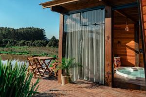 a house with a deck with a hot tub and a table at Cabanas Doce Recanto in Bom Retiro