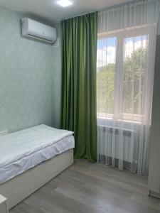 a bedroom with a bed and a window with green curtains at Dream home in Vanadzor