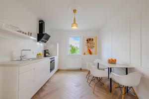 a kitchen with white cabinets and a table and chairs at Hanse Villa - Apartment Lübeck in Lübeck