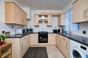 a kitchen with wooden cabinets and black counter tops at Immaculate Condition 3 Bed En-Suite Refurbished House in Goodmayes