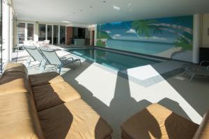 uma piscina com um sofá e cadeiras numa casa em Luxurious Villa 't Kasteelhof em Veulen