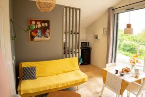 a living room with a yellow couch and a table at Spa nordique avec vue sur la campagne in Saint-Paul-Lizonne