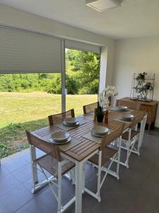 a dining room table with chairs and a large window at Seljani in Pluzine
