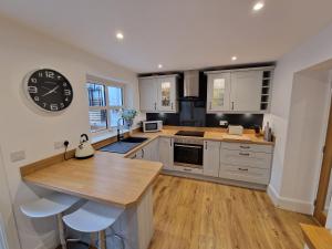 une cuisine avec une grande horloge murale dans l'établissement Law Common Cottage, à Hepworth