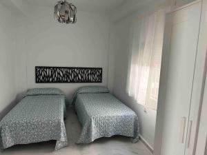 two beds in a room with white walls and a window at Chalet a 2 metros de la playa in Rota