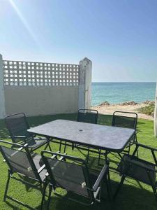a table and chairs sitting on the grass near the ocean at Chalet a 2 metros de la playa in Rota